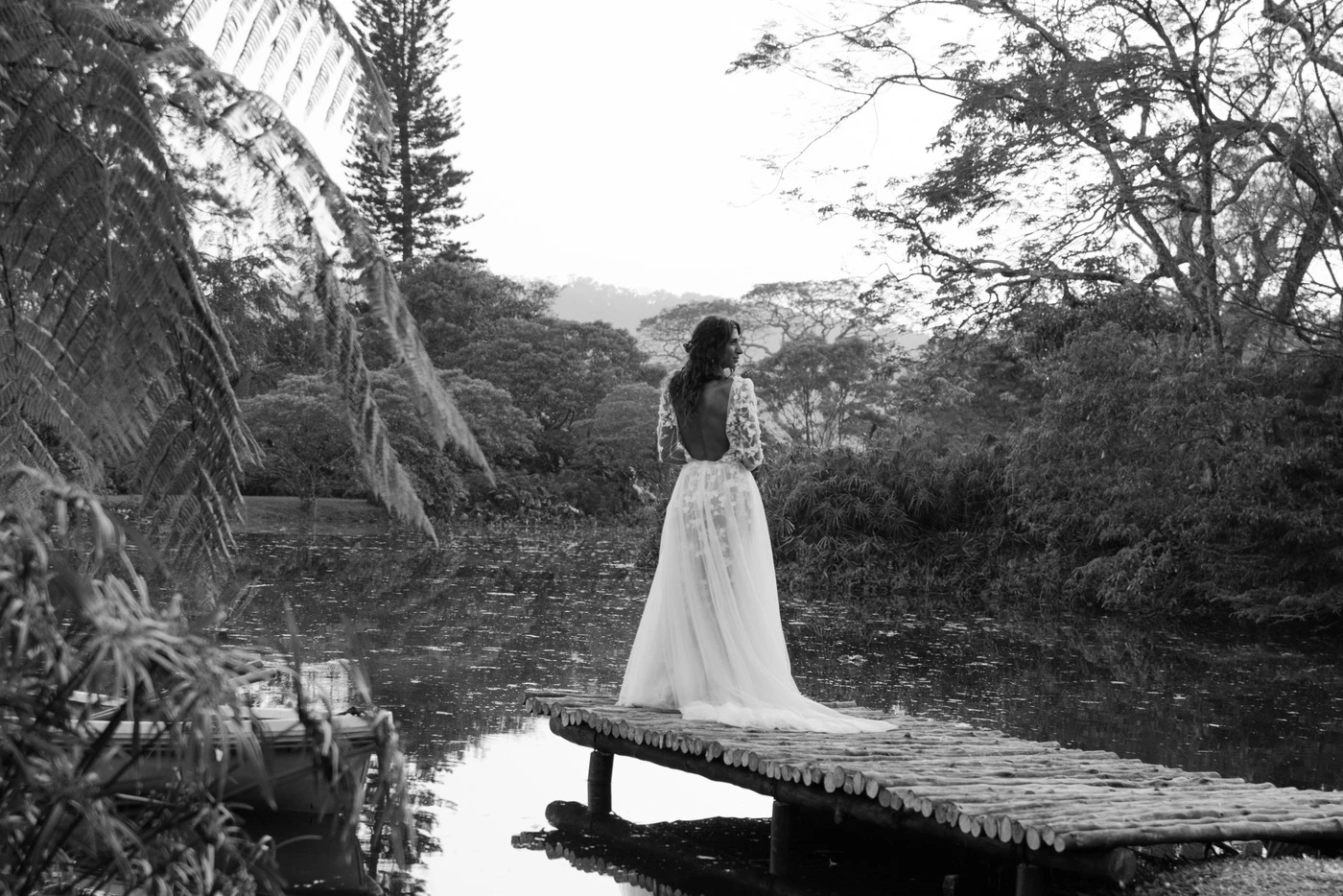 Bride on the pond dock beneath the trees, black and white