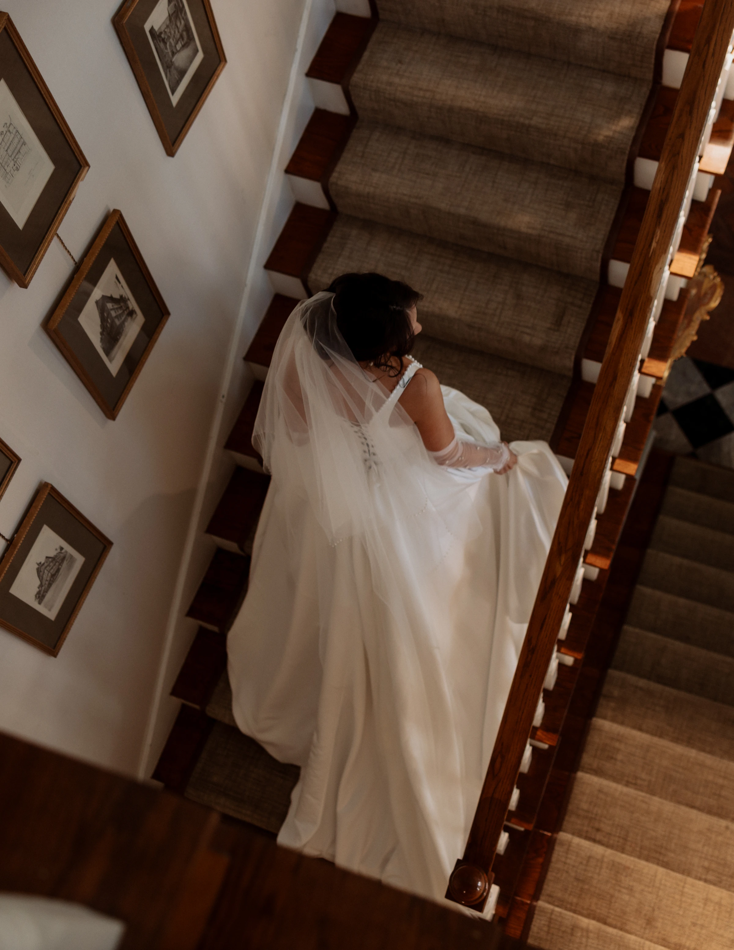 Tasia carrying her train down the staircase at La Caille, photographed from above