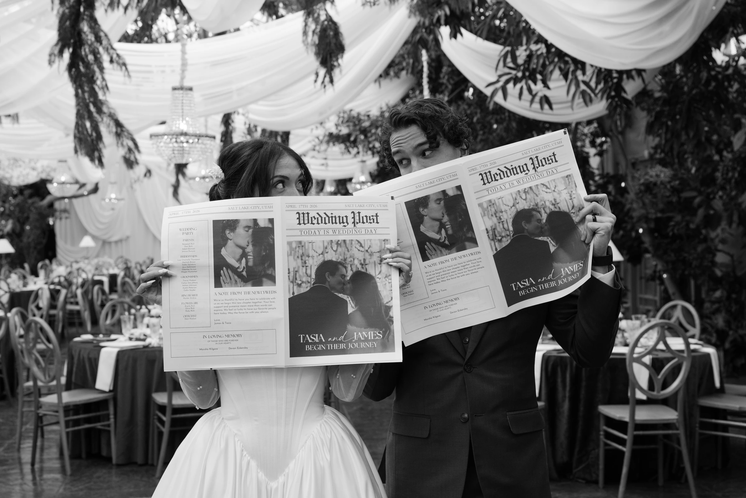 James and Tasia peeking over their custom Wedding Post newspapers at the La Caille reception, black and white