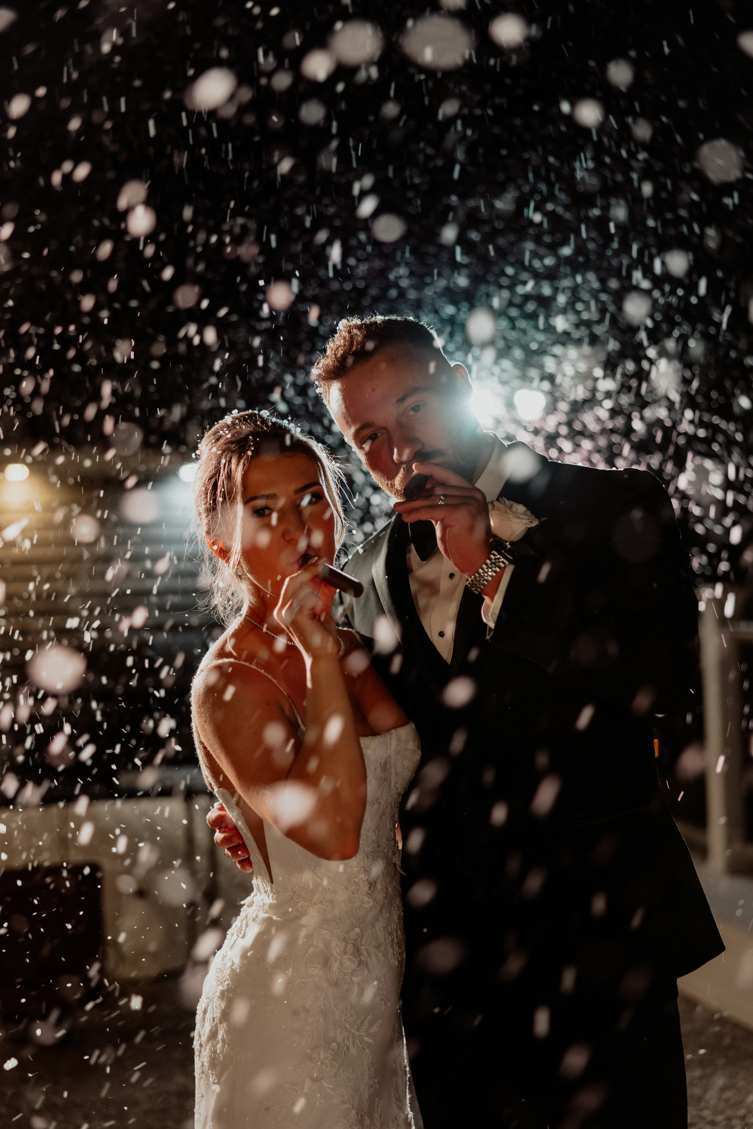 Meghan and Tyler sharing cigars in the falling snow at night outside The Piermont